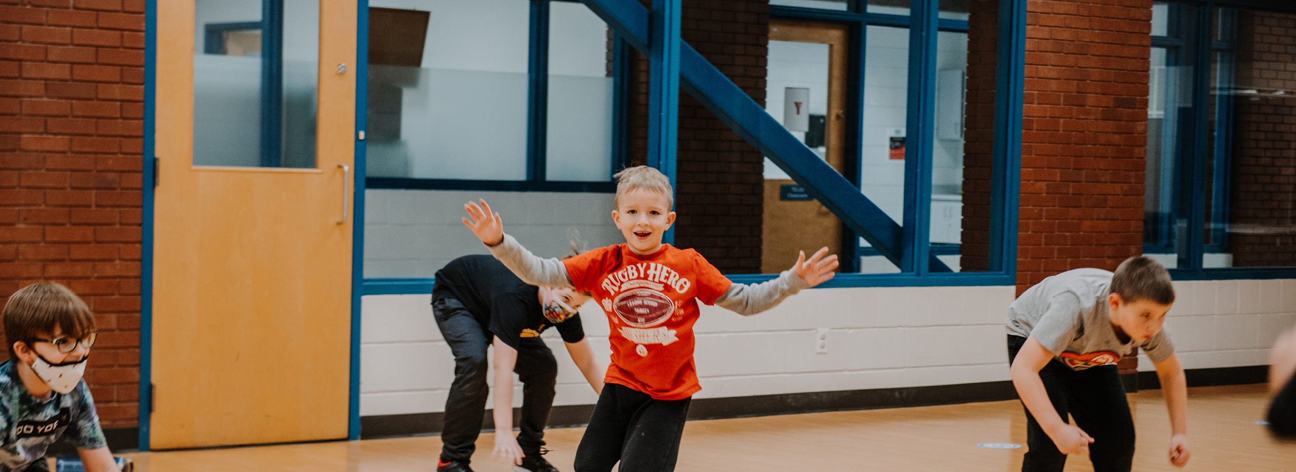 A young boy runs inside a studio space with his arms in the air.