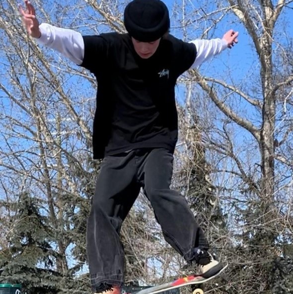 person doing a skateboard trick in front of trees