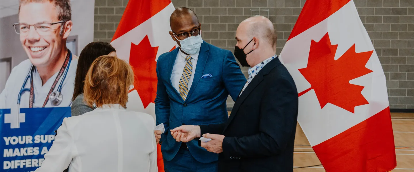 A group of well-dressed men and women stand together after a media event.
