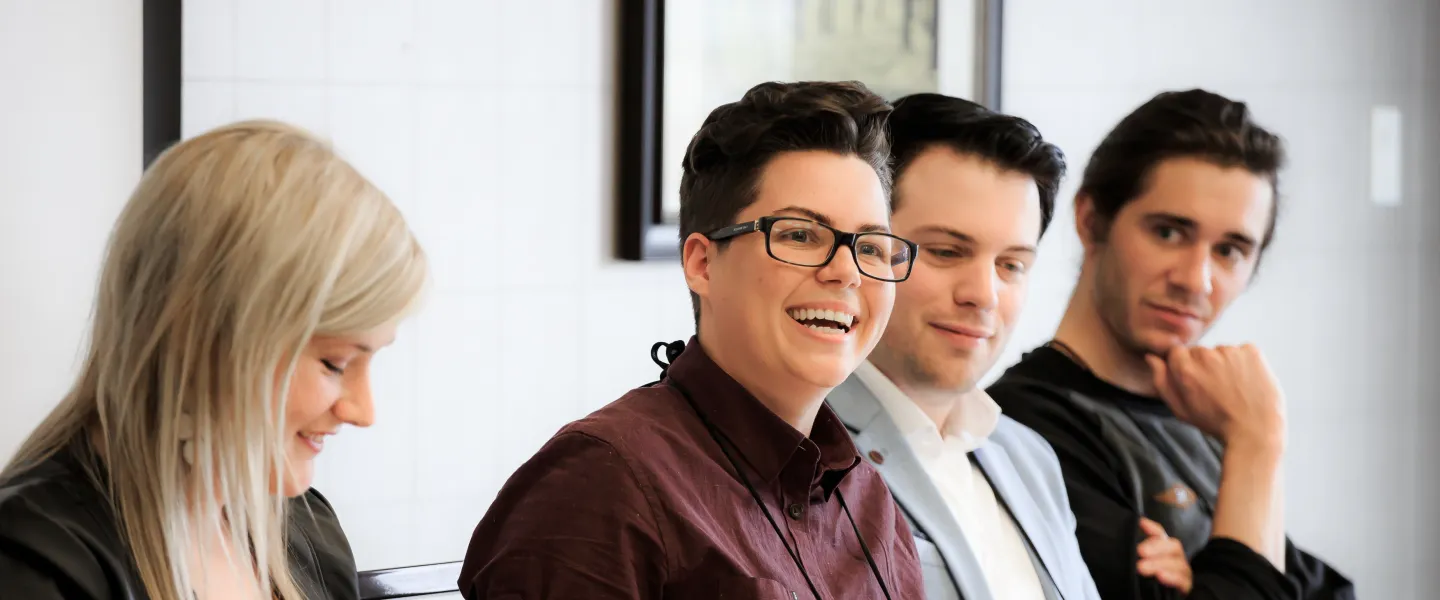 A group of well dressed young adults sit at a head table during a conference.