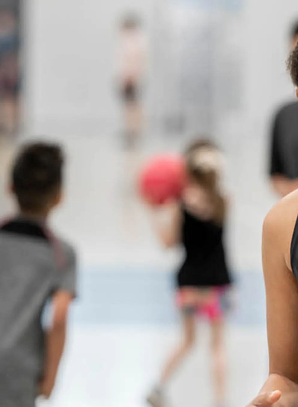 A young girl holds a basketball in a gymnasium.