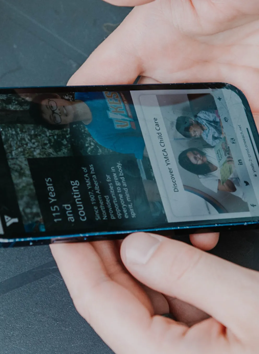 a person holding a phone browsing YMCA website