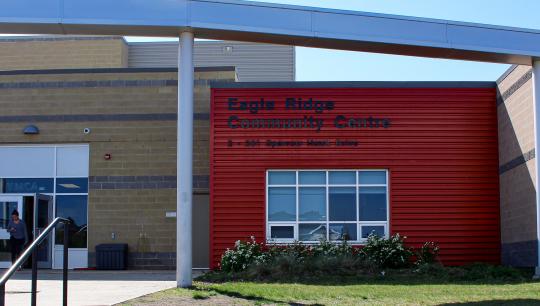 A modern brick building features a stainless steel arch that goes over the main walkway.