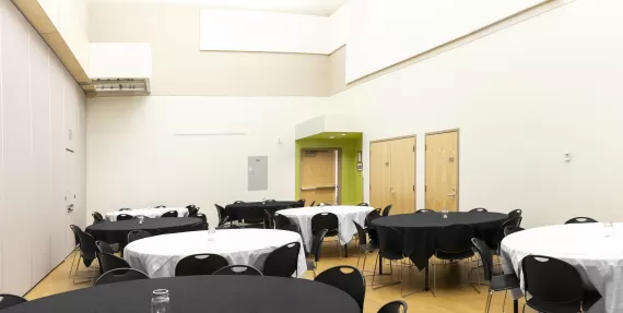 many round tables and chairs covered in black and white table cloths