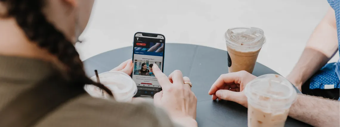 A women points to her cell phone and shows it to two people sitting beside her.