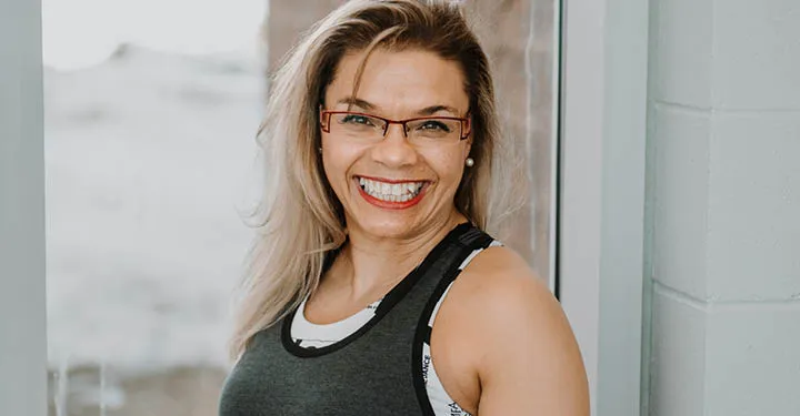 A woman wearing a YMCA uniform poses infront of a large window.